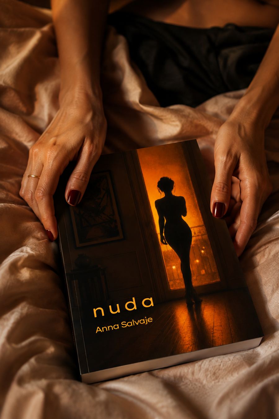 Il libro Nuda tenuto da due mani su lenzuola color cipria